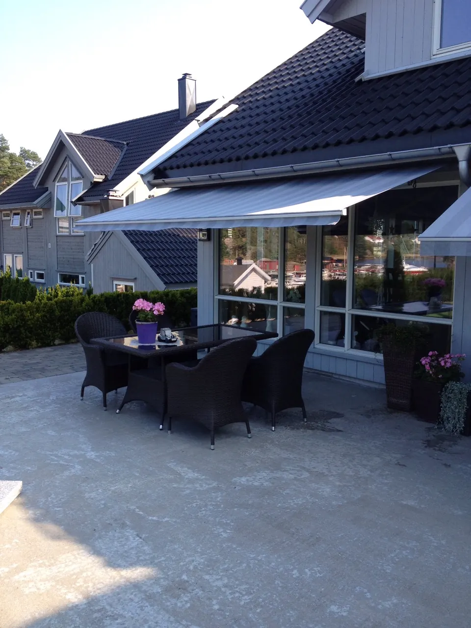 Sort terrassemarkise over en uteplass ved vannet